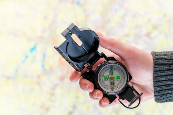 Kompass i en kvinnlig hand att söka efter saknade personer på en backg — Stockfoto
