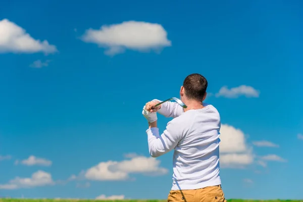 Masculino golfista ao bater a bola vista de volta ao campo — Fotografia de Stock