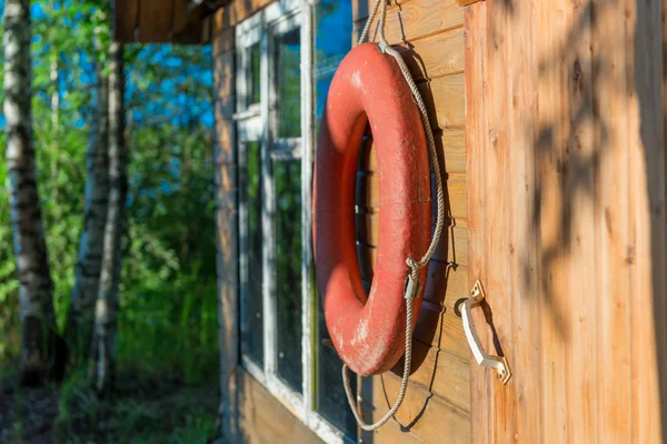 Old lifebuoy close-up on a wooden wall of a rural house near a l — Stock Photo, Image