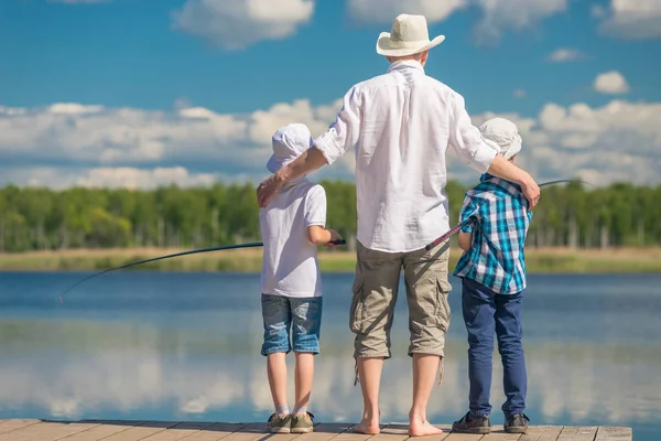 Feliz padre con hijos en un viaje de pesca en un hermoso lago — Foto de Stock