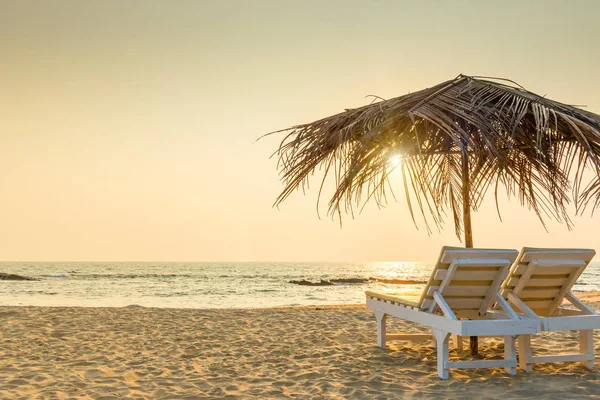 Empty chairs under thatched umbrellas on a sandy beach. Tinted. — Stock Photo, Image