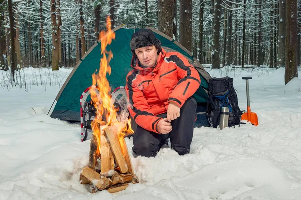 A tourist in a winter forest in extreme conditions is building a — Stock Photo, Image