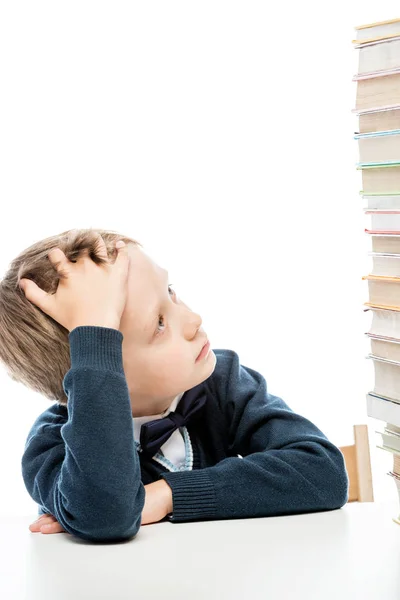 Portrait of a tired boy with a pile of books on a table isolated — Stock Photo, Image