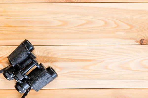 Binoculars on a wooden background in the corner of the frame, sp — Stock Photo, Image