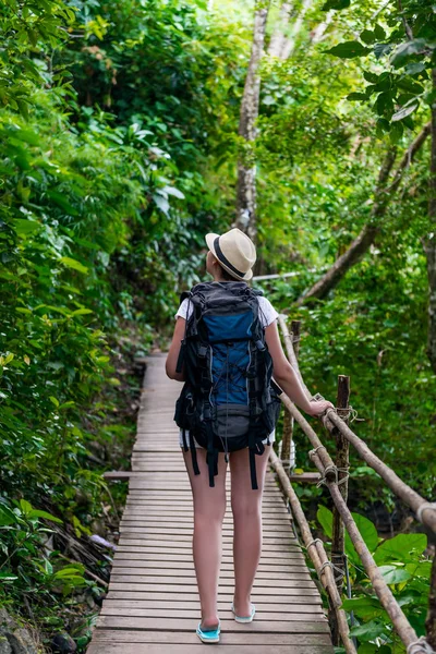 Flicka turist med en stor ryggsäck i Asien på en trä spår — Stockfoto