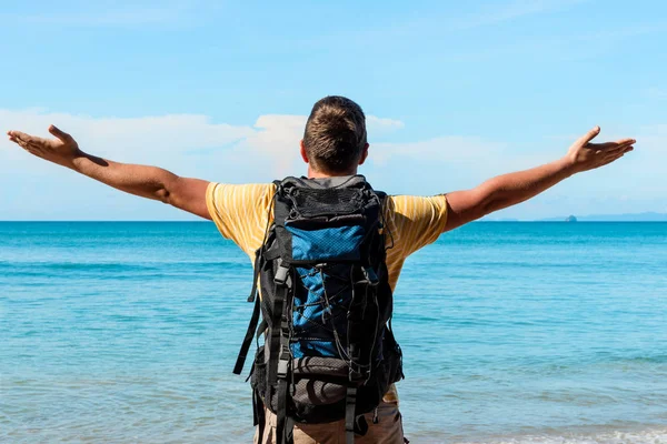 Turista con una gran mochila en la playa con las manos extendidas — Foto de Stock