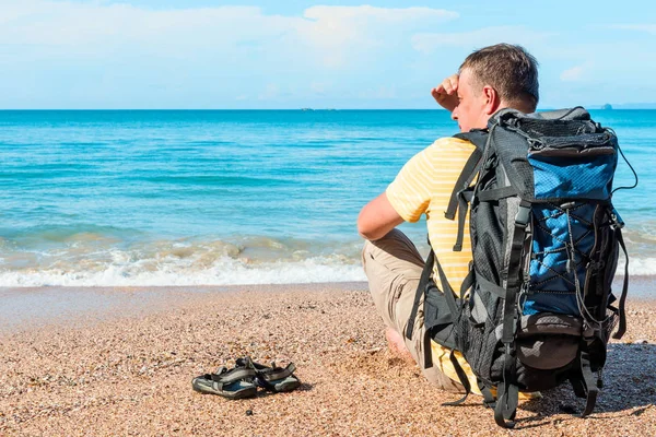 Viajero con una mochila descansando en la playa cerca del mar en Th — Foto de Stock