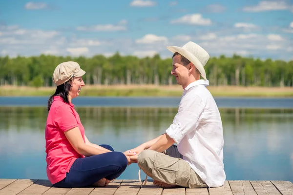 Młoda żona i mąż na drewnianym molo w pobliżu jeziora są odpoczynku — Zdjęcie stockowe