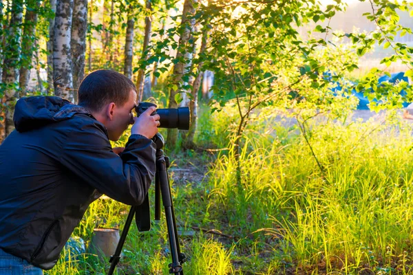 Un hombre con una cámara en un trípode toma fotos de la naturaleza — Foto de Stock