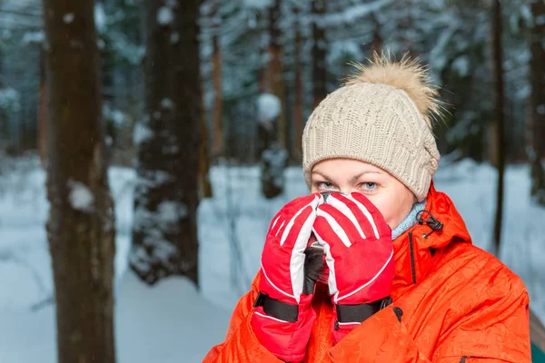 Mujer en ropa de invierno calentada en el bosque de invierno con té caliente —  Fotos de Stock