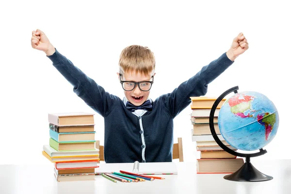Angry boy at table with books and globe against white background — Stock Photo, Image