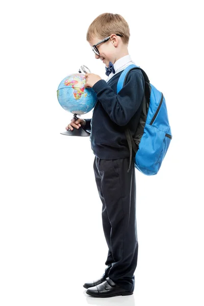 Ritratto di uno scolaro con lente d'ingrandimento e globo su un dorso bianco — Foto Stock