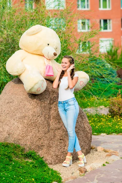 Vertikales Porträt eines schönen Mädchens mit einem riesigen Bären in der Hand — Stockfoto