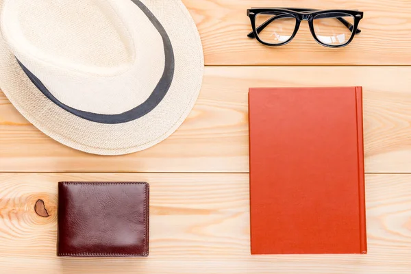Hat, glasses, interesting book and wallet with money on wooden b