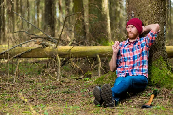 Holzfäller legte nach der Arbeit seine Axt ab und setzte sich unter einen Baum — Stockfoto