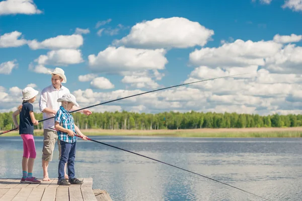 Счастливая семья на рыбалке - отец, сын и дочь с рыбалкой — стоковое фото