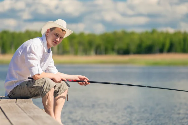 Experienced fisherman sitting on a wooden pier and fishing in th — Stock Photo, Image