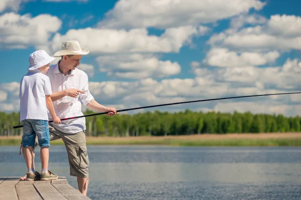 El pescador enseña a su hijo a pescar en una caña de pescar — Foto de Stock