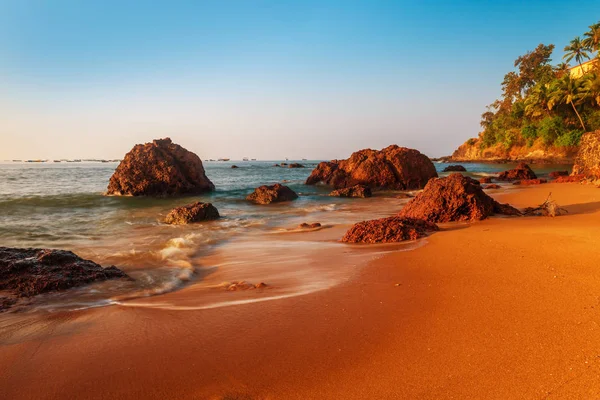 Playa de arena y grandes rocas en el agua de mar. Teñido en rojo . — Foto de Stock