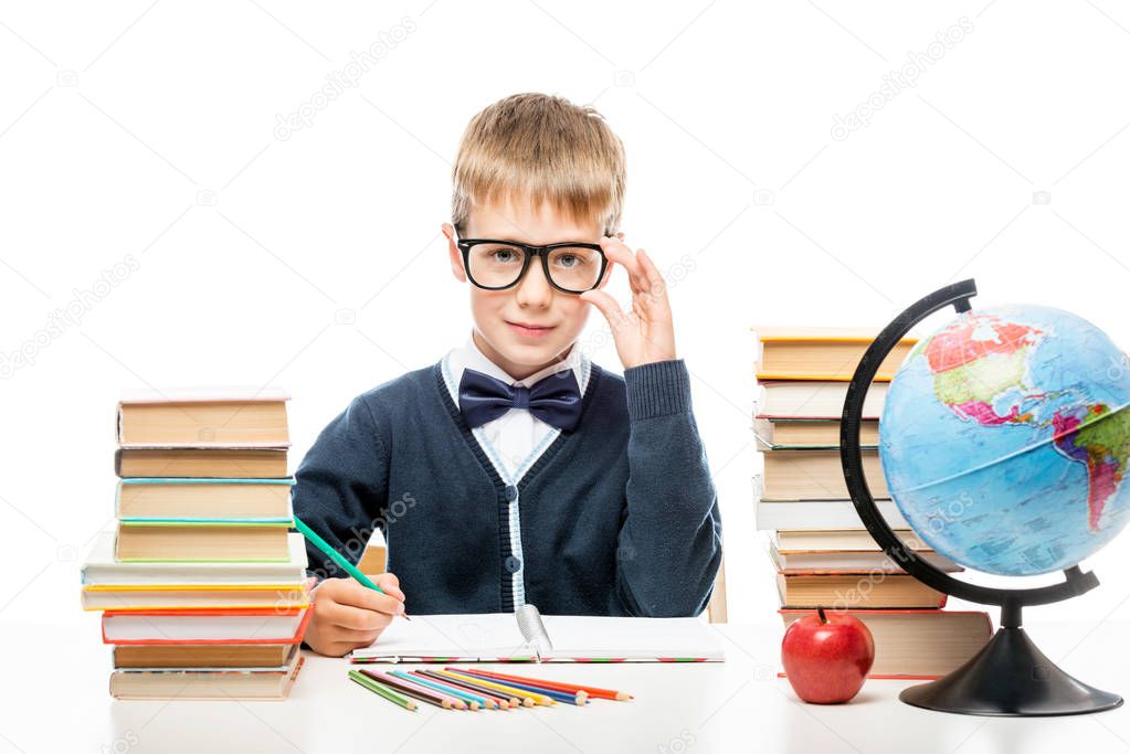 portrait of a happy smart schoolboy at the table with books on a