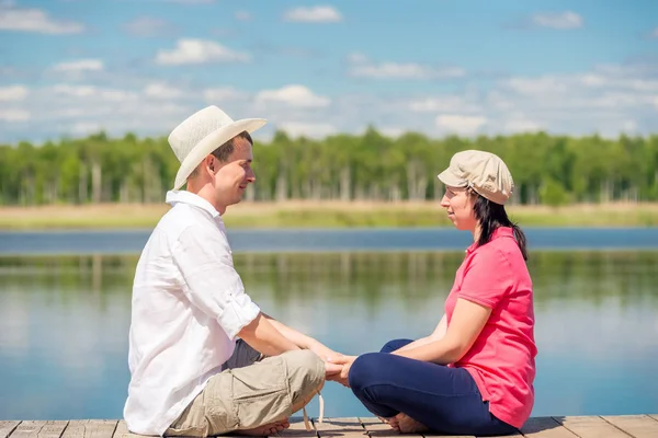 Žena a muž na dřevěném molu v blízkosti jezera odpočívá — Stock fotografie