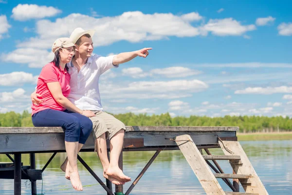 Para 30-letni odpoczynek na molo, człowiek, wskazując na jezioro — Zdjęcie stockowe