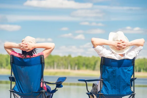 Family on chairs resting near a beautiful lake on chairs, view f — Stock Photo, Image