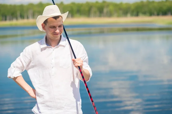 Retrato de un pescador feliz en un sombrero blanco en un fondo del lago — Foto de Stock