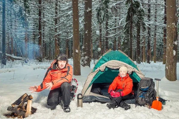Tourists in the winter forest - a man is warming his hands by th — Stock Photo, Image