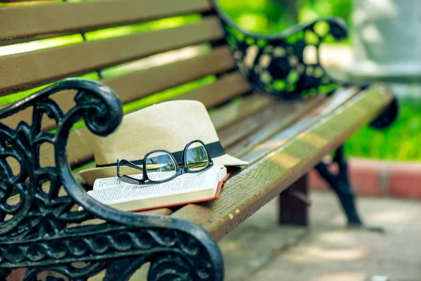 Ein aufgeschlagenes Buch, stylische Brille und Strohhut liegen gleichauf — Stockfoto