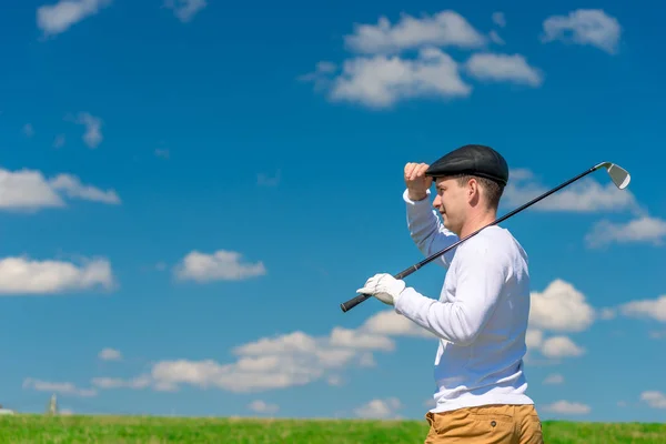 Ein Golfer mit Mütze und Golfschläger auf der Schulter schaut in die Runde. — Stockfoto