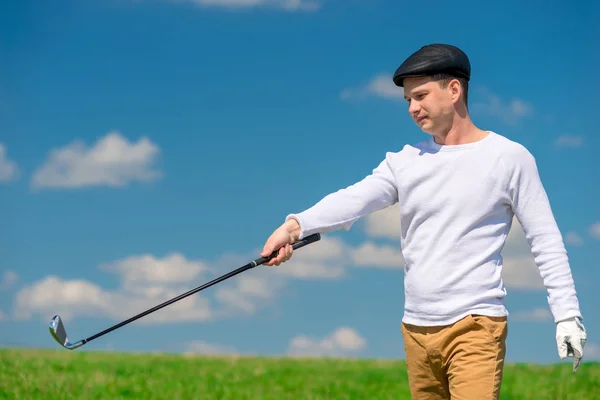 Unga golfare i en hätta och golf club på en grön spelplan — Stockfoto