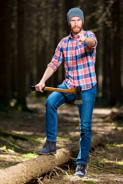 Um silvicultor barbudo com um machado aponta para a câmera com seu fing — Fotografia de Stock