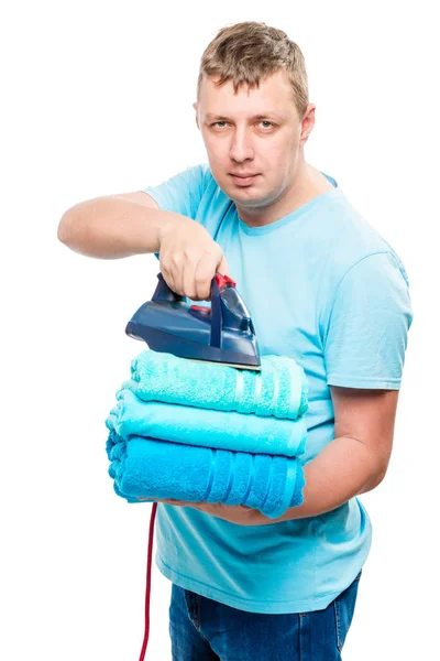 Retrato hombre con plancha y una pila de toallas planchadas aisladas —  Fotos de Stock