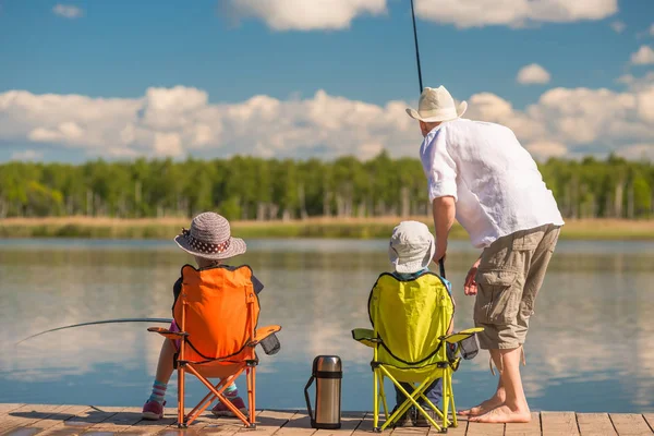 Padre con il figlio e la figlia su un molo di legno nel lago fi — Foto Stock