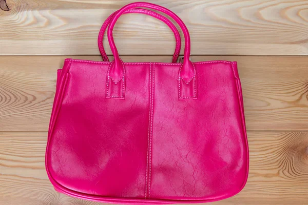 Rózsaszín elegáns női táska, a fa padló felülnézet — Stock Fotó