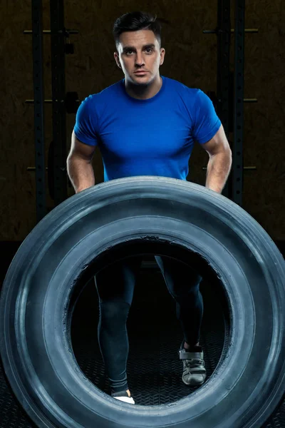 Ritratto di un atleta forte con una grande ruota pesante in palestra — Foto Stock