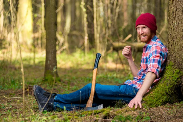 Glücklicher Holzfäller, der sich in der Nähe eines Baumes im Wald ausruht — Stockfoto
