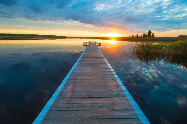 Krásná krajina - dlouhé dřevěné molo a nastavení slunce ove — Stock fotografie