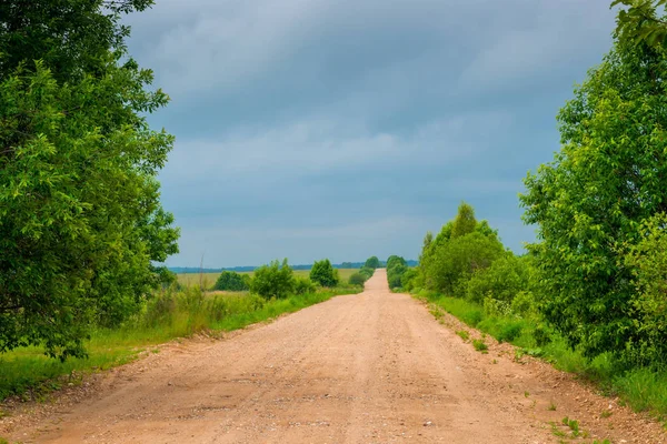 The unpaved road is empty, the sky is dark clouds — Stock Photo, Image