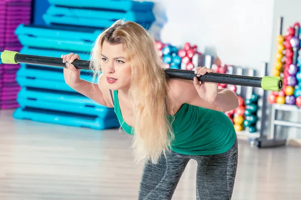 Beautiful blonde with a dumbbell doing sit-ups in the gym — Stock Photo, Image