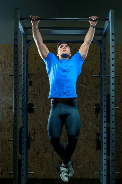 Portrait d'un athlète dans la salle de gym sur l'équipement tire vers le haut — Photo