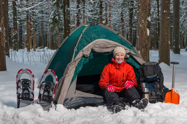 Glückliche Aktivtouristin sitzt im Winterwald im Zelt — Stockfoto