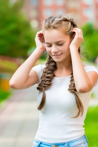 Beautiful girl with two braids corrects hands hair, close-up por — Stock Photo, Image