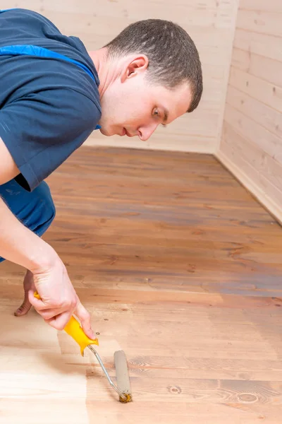 Working roller paint on a wooden floor in the building — Stock Photo, Image