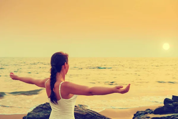 Ragazza con le mani divaricate al tramonto sul mare. Colorato . — Foto Stock