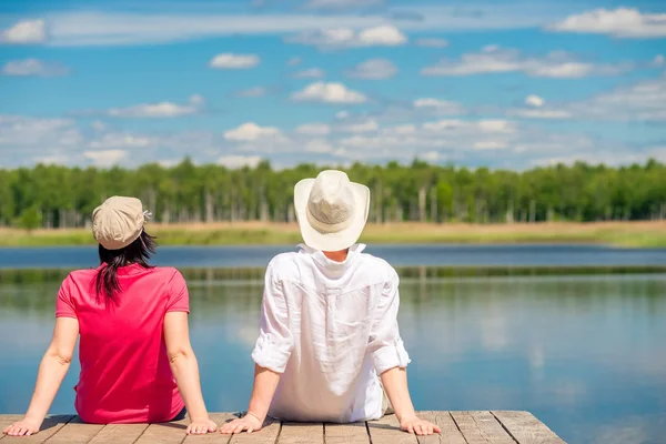 Pasangan yang mencintai menikmati indah danau duduk di kayu pi — Stok Foto