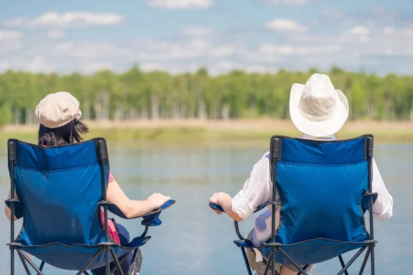 A loving couple sitting on chairs near a beautiful lake on a pie — Stock Photo, Image