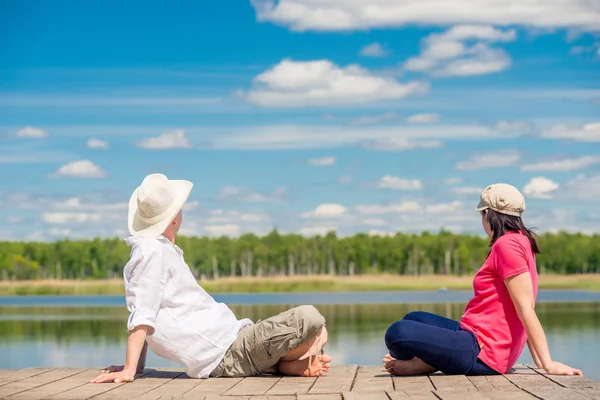 Man en vrouw op een houten pier zitten en genieten van het mooie meer — Stockfoto