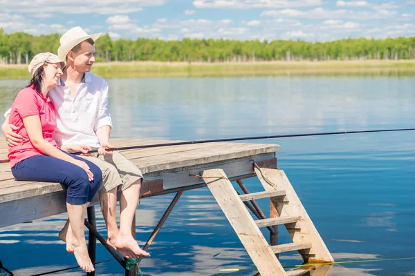 Un couple marié sur une jetée avec les pieds nus attraper un poisson sur un b — Photo